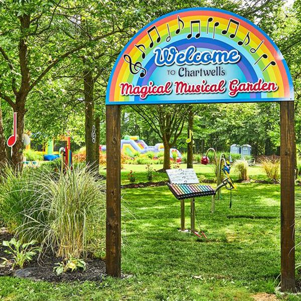 a rainbow shaped and colored sign welcoming people to the Chartwell Happy Day Camp