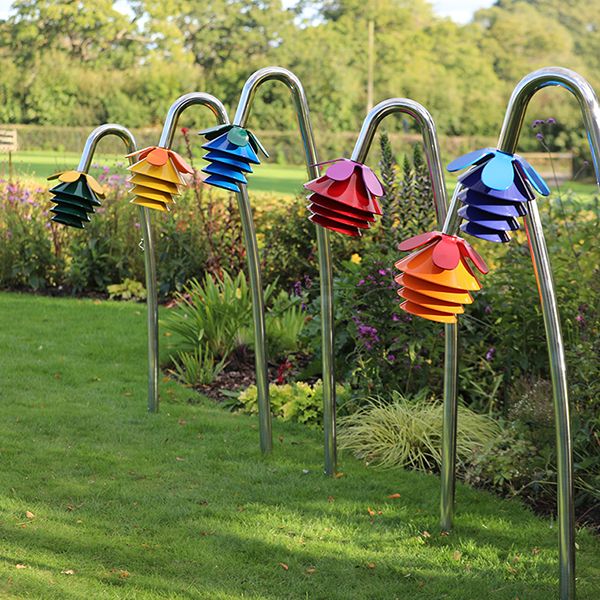 a row of Harmony Outdoor Musical Flowers all with different coloured bells and petals in a sensory garden or park