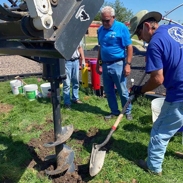 three men from Hastings Noon Kiwanis team installing outdoor musical instruments in the Alcott Elementary School Playgound