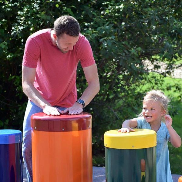 father and daughter playing rainbow samba outdoor drums in st feriole memorial gardens music park