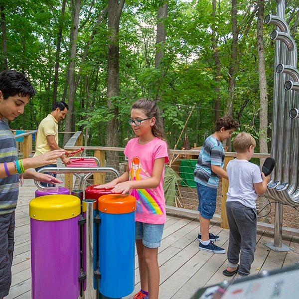 children playing on the outdoor musical instruments at the Treetop Outpost at Conner Prairie History museum