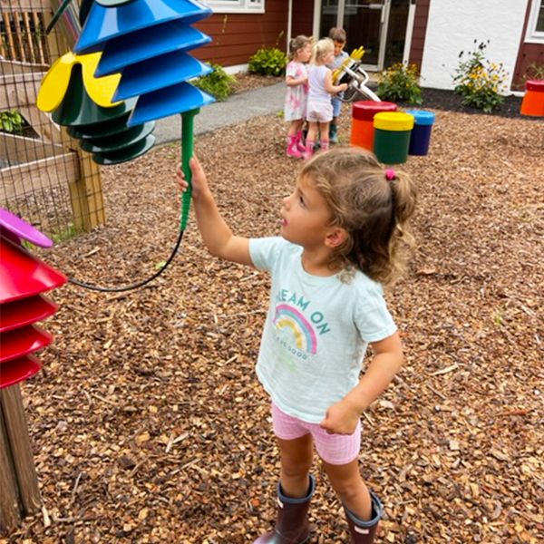 young girl playing a blue flower shaped musical instrument