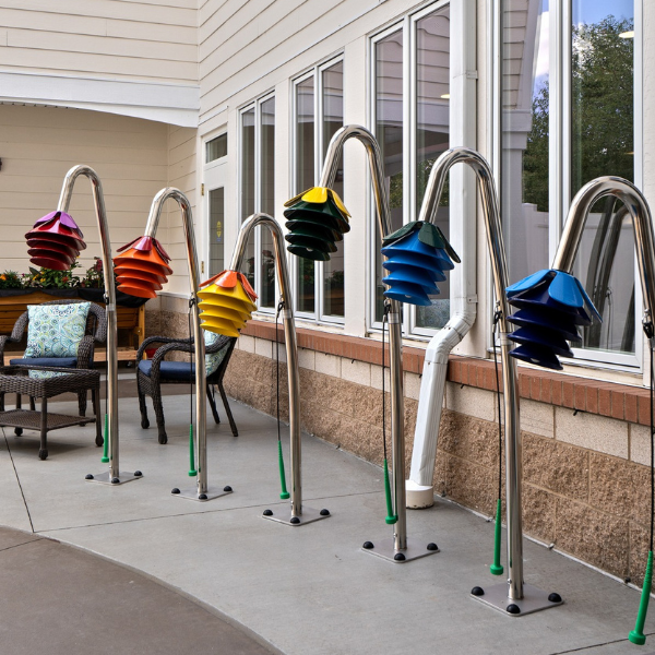 a row of outdoor musical instruments shaped like flowers all in different colours in a senior living courtyard or porch