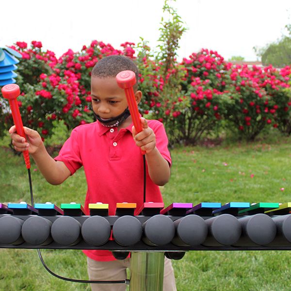 School child playing colorful outdoor xylophone at the Lift for Life Academy