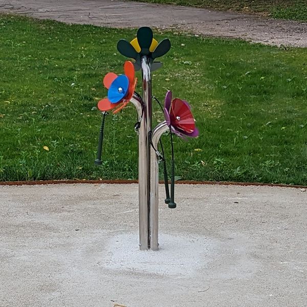 a colorful bunch of outdoor chimes shaped like large flowers on a pathway