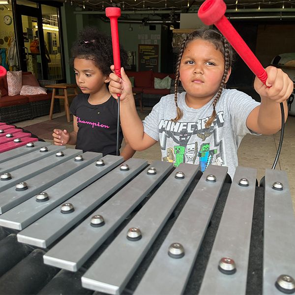 Two girls playing an outdoor xylophone in the Madison Childrens Museum 