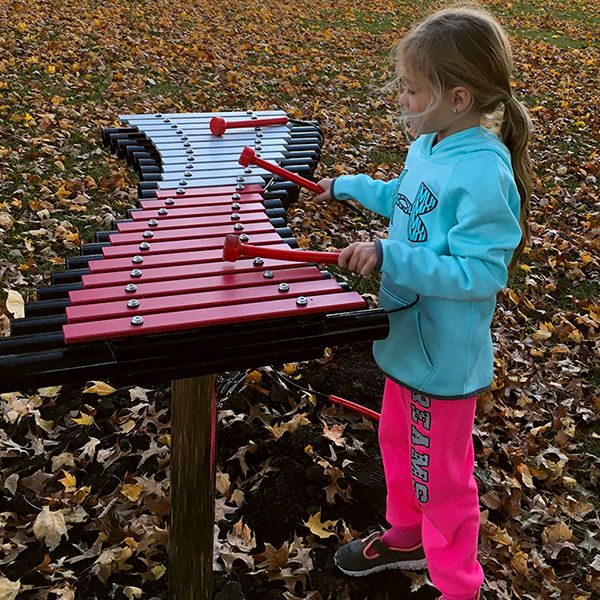 Little girl playing a large outdoor xylophone in Anderson Park City of Essex