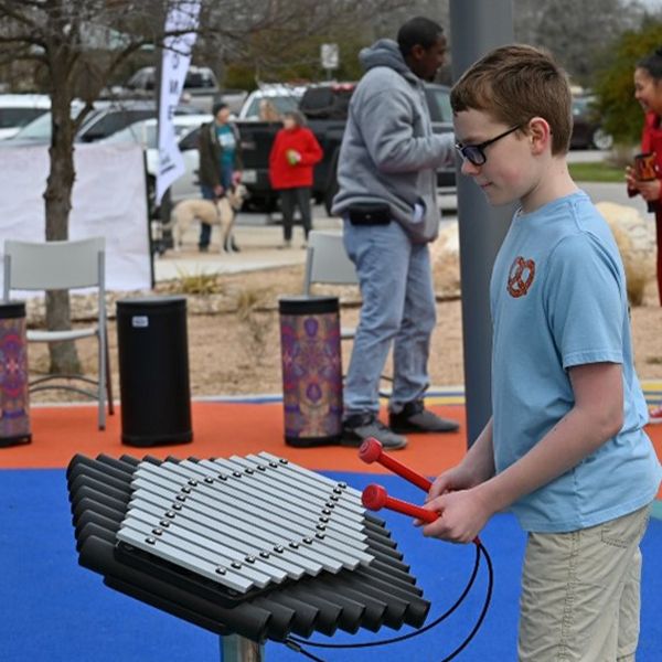 a young teenage boy playing an outdoor musical instrument or xylophone