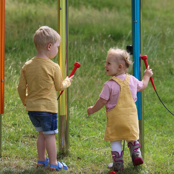 two young children playing on rainbow coloured chimes in a playground