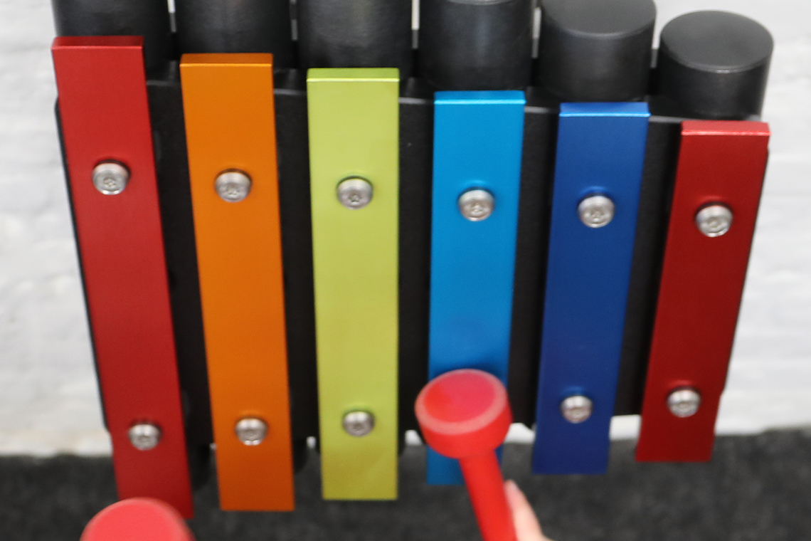 a small rainbow coloured outdoor metallophone for wall mounting suitable for nurseries and kindergartens