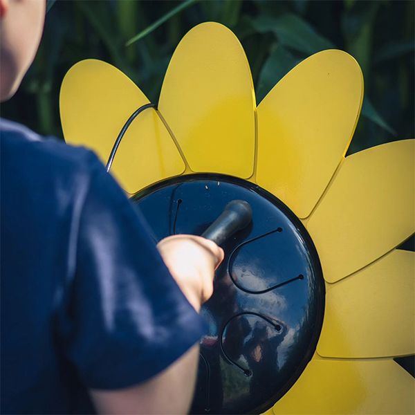 Boy playing an outdoor drum shaped like a giant  sunflower