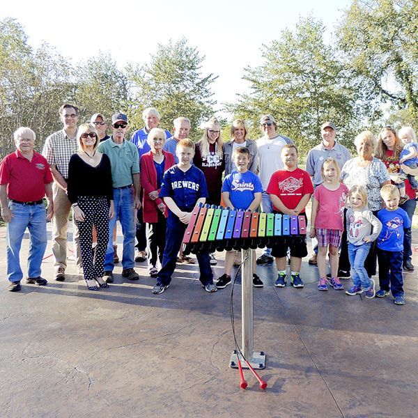 Family standing in front of a rainbow cavatina xylophone at a st feriole memorial gardens music park opening