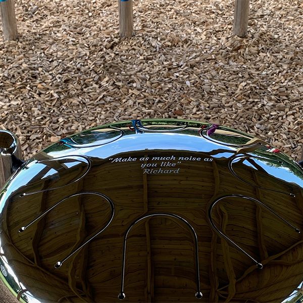 Outdoor steel tongue drum engraved with the memorial inscription 'Make as Much Noise As You Like' by Richard at the Thomas Centre.