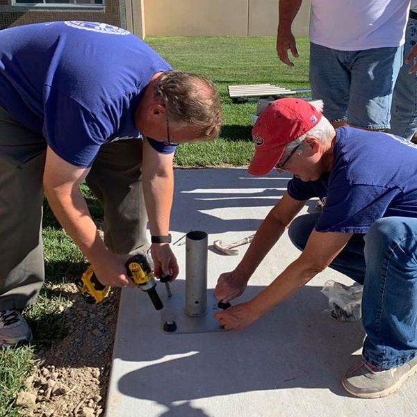 three men from Hastings Noon Kiwanis team installing outdoor musical instruments in the Alcott Elementary School Playgound