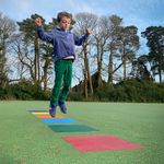 a young boy in a playground jumping onto colored squares that make a musical  tone when activated