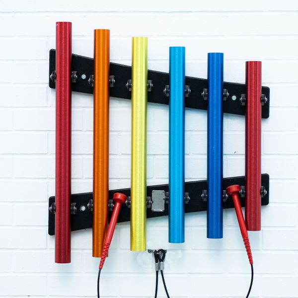 rainbow colored outdoor musical chimes attached to a white wall in the Edinburgh Children's Hospital music garden