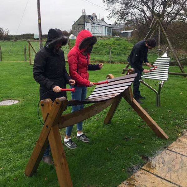 family playing outdoor musical instruments in the garden of Calums Cabin Isle of bute