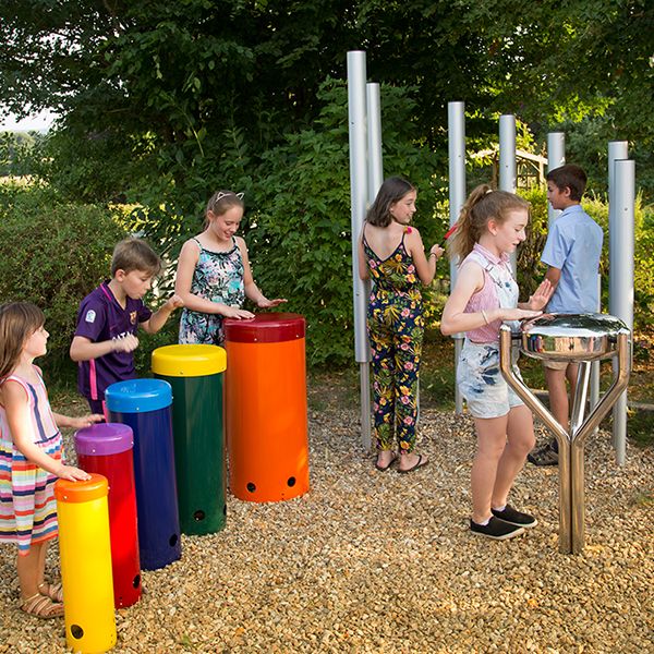 four children playing a group of outdoor musical instruments in a playground 