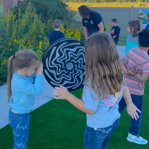 two children playing on a large rain wheel in the Kansas Wetlands Center new musical garden