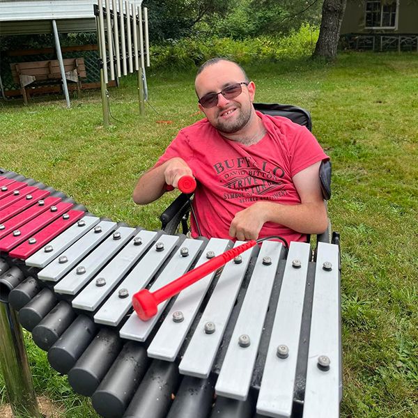 Man in a wheelchair playing outdoor xylophone in the camp beausite new musical garden