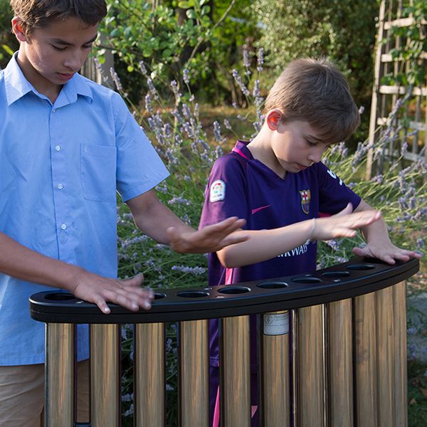 two boys playing a set of handpipes in a park