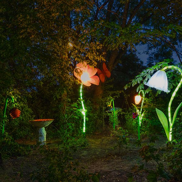 outdoor musical flowers and flower sculptures lit up at night in a sculpture garden