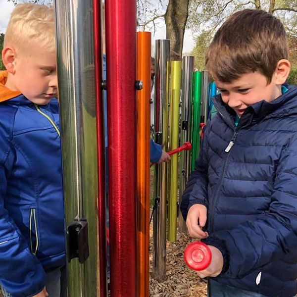 schoolboys playing bright colorful outdoor musical chimes in the school playground