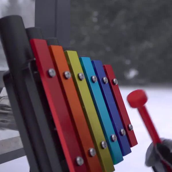 a small rainbow colored outdoor xylophone being played in the snow