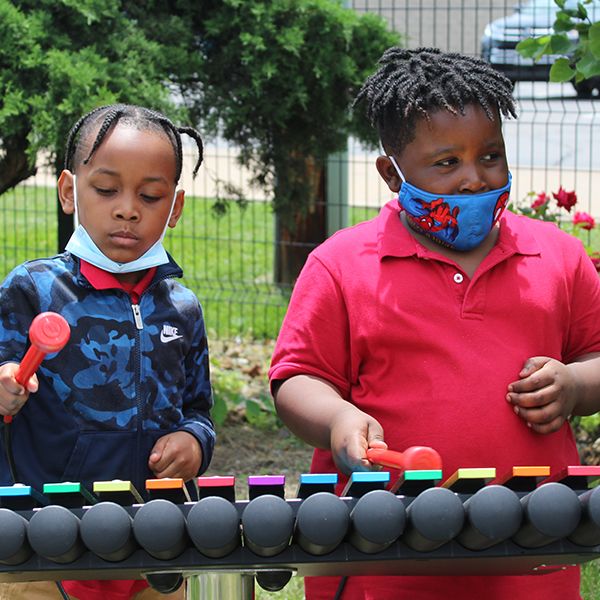 School children from the Lift For Life Academy playing colorful outdoor xylophone in their schoolyard