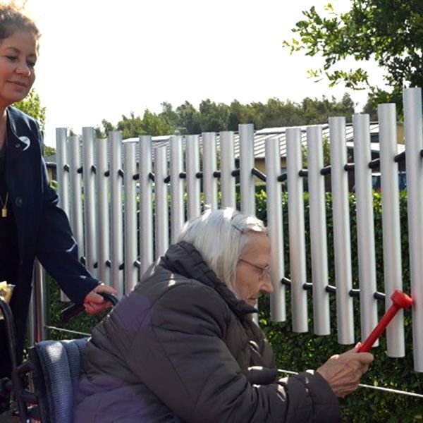 older lady in a wheelchair playing an outdoor musical instrument