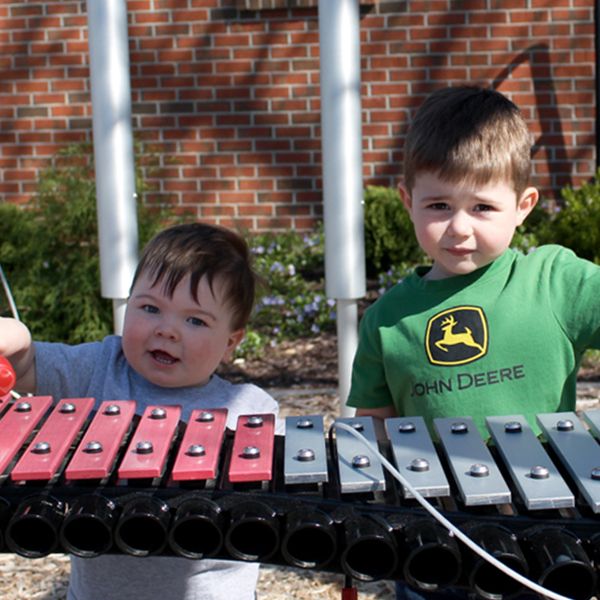 two little boys playing on an outdoor xylophone in the grounds of the children's healing center