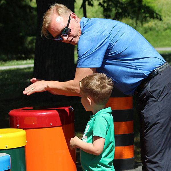 an man and little boy playing on a colourful outdoor drums in the belleville rotary music garden 