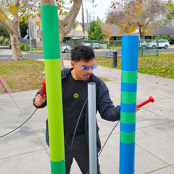 man playing outdoor musical chimes wrapped in bright colored vinyl