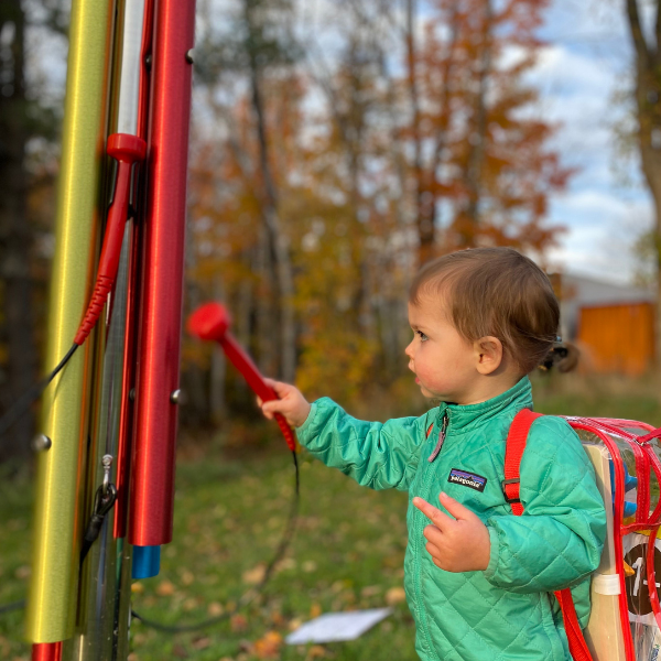 a young boy wearing a rucksack playing an outdoor musical chime in the Bethlehem Public library 