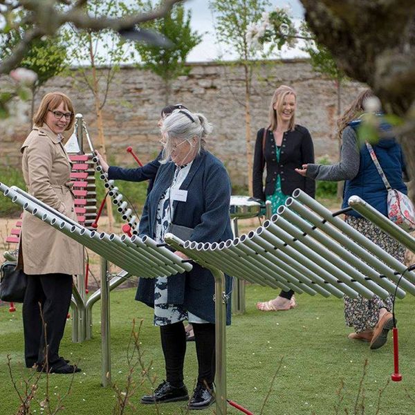 a group of ladies playing on the collection of outdoor musical instruments in the playful garden in Brodie Castle, National Trust Scotland