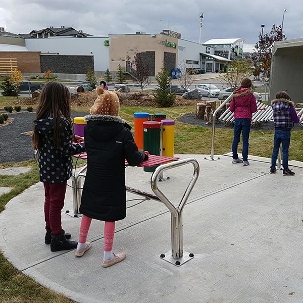 a collection of outdoor musical instruments being played in the outdoor classroom at Buffalo Rubbing Stone Elementary School in Canada