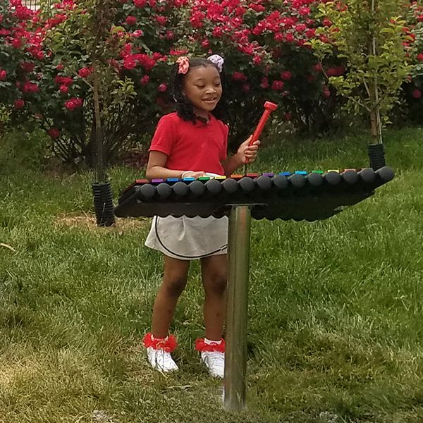 School child playing colorful outdoor musical xylophone at the Lift for Life Academy