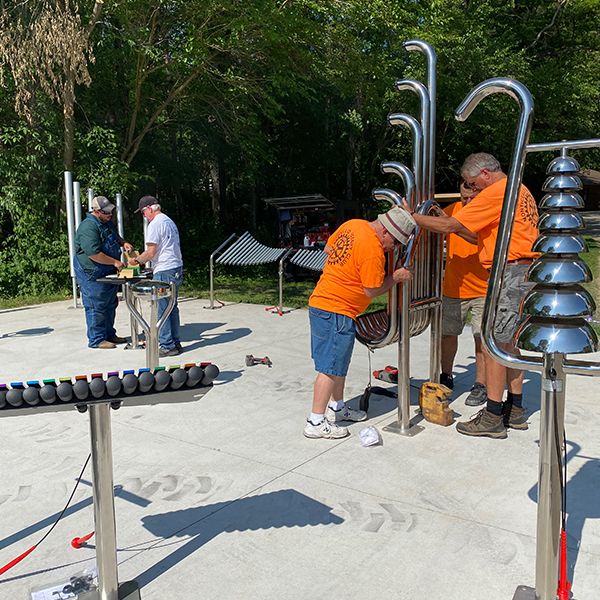 a team of Rotary volunteers installing large outdoor musical instruments in a new music park at camp courageous