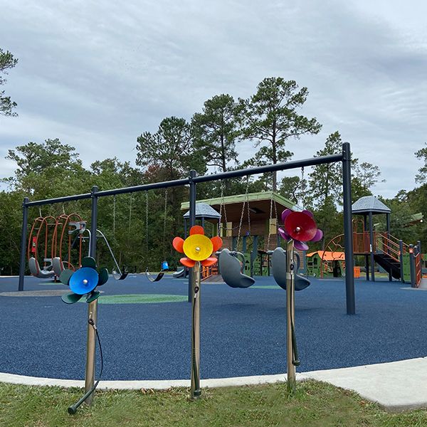 three musical chimes shaped like daisy flowers on stainless steel legs in an inclusive playground