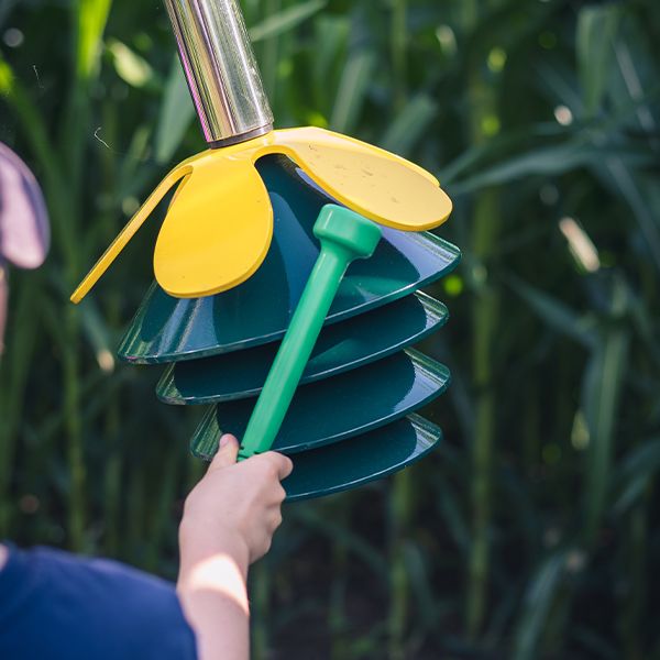 an image of a green mallet striking an outdoor musical instrument made to look like a green flower 