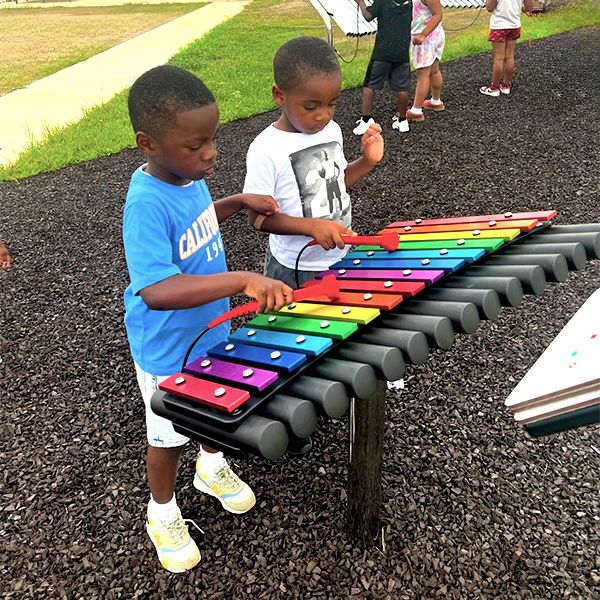 two young boys playing a rainbow colored outdoor xylophone at dayton metro library