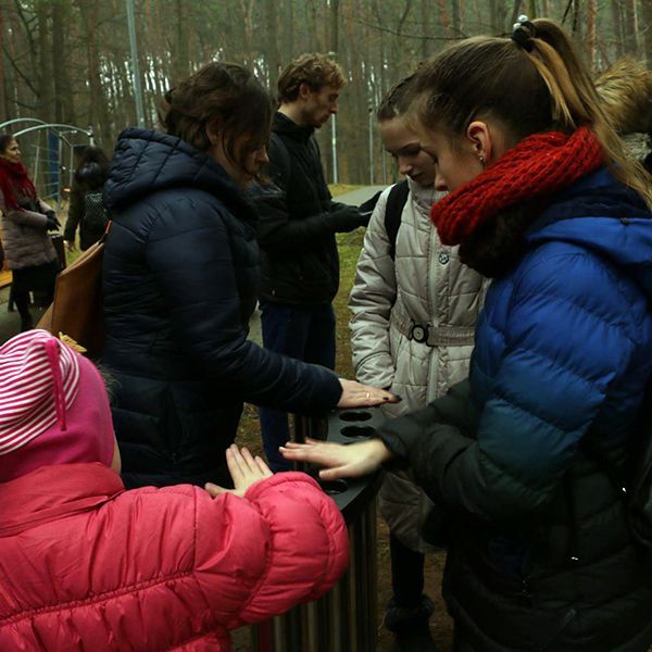 Family playing a stainless steel handpipe instrument in a city park