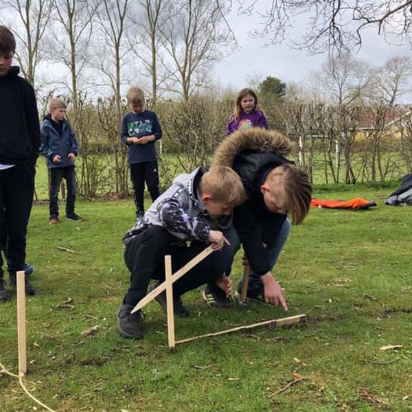 two schoolboys measuring between two stakes in the ground ready for new outdoor musical instruments