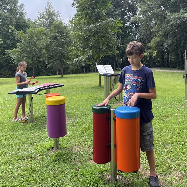 Two children playing colorful drums and xylophone in a playground