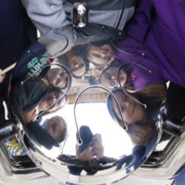 faces being reflected in the shiny surface of a stainless steel babel drum from percussion play