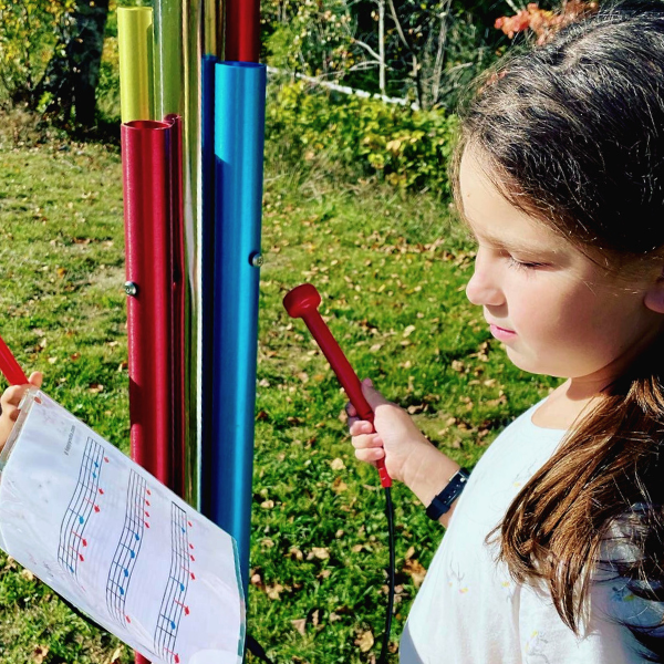 a young girl playing a rainbow colored musical chime post in the bethlehem public library music garden