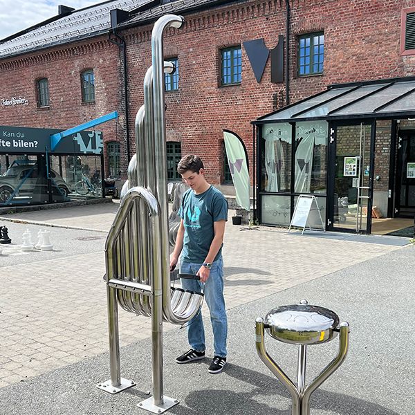 male teenager playing a tall stainless steel outdoor musical instrument outside the Vitensenteret Innlandet Science Centre in Norway