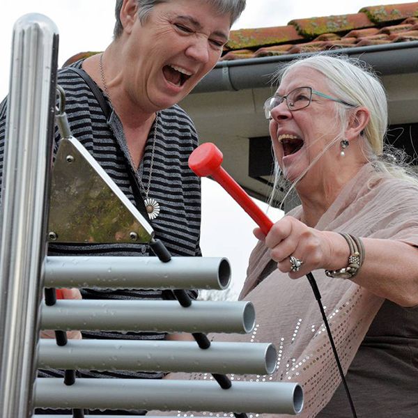 Two older ladies playing an outdoor vertical harmony xylophone from percussion