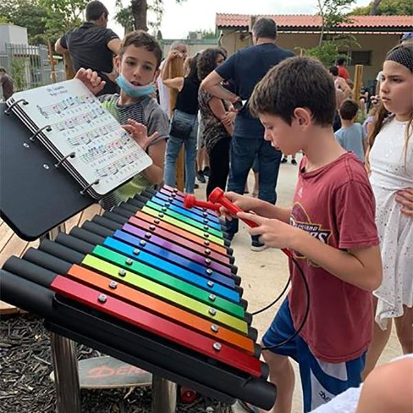 young boy playing a rainbow colored outdoor xylophone in the Kibbutz Magal musical memorial playground