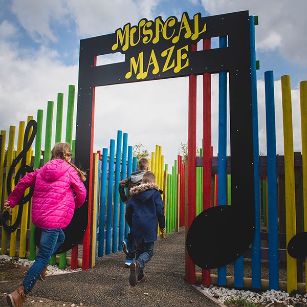 three children running into the entrance for the music maze at the National Forest Adventure Farm 